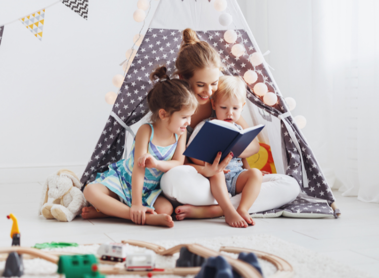 Image of a mother reading to her 2 children in a makeshift tent at home.