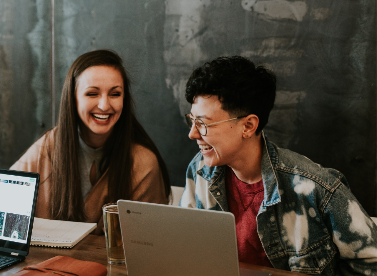 Image of two people sitting at a table laughing