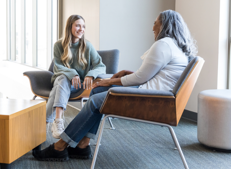 Two women sitting together and talking to each other.