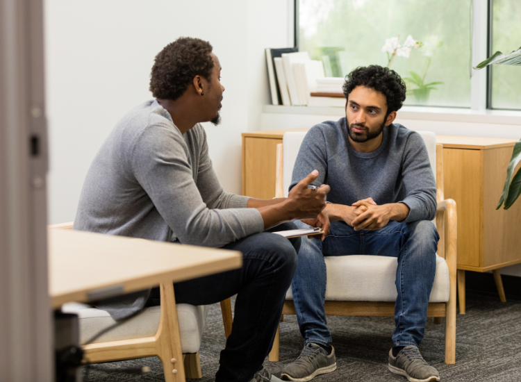 Photo of two males sitting together and having a serious conversation.