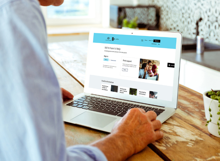 An elderly person using a laptop that has the Services NSW homepage on the screen.