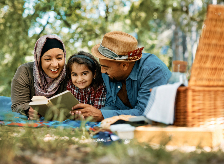 Image of a family happily having a picnic and reading a book together