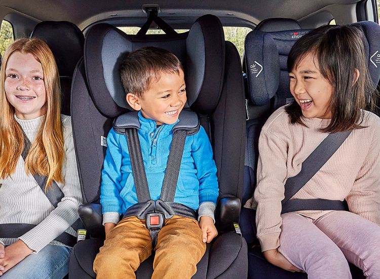 three children seated on the back seat of a car in car seats and seatbelts visible