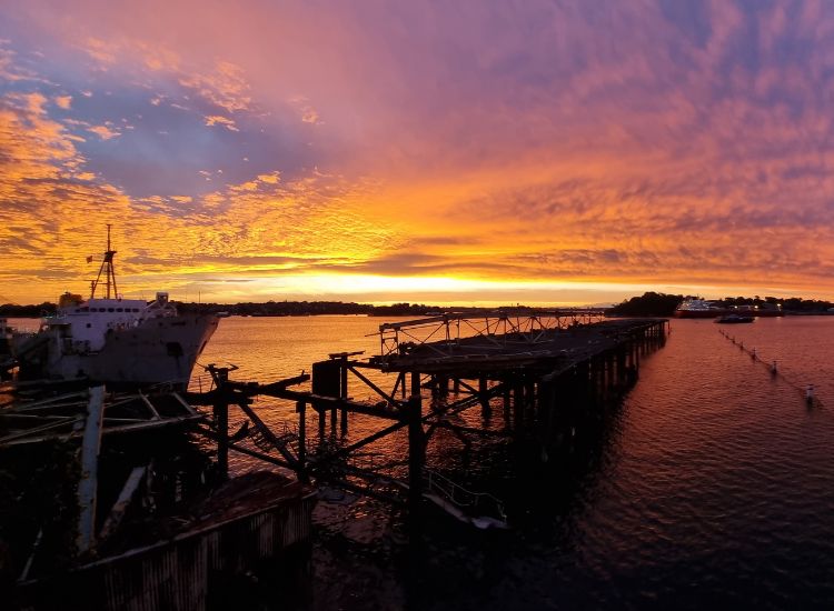 beautiful sunset with light oranges, purples and blues over a wharf