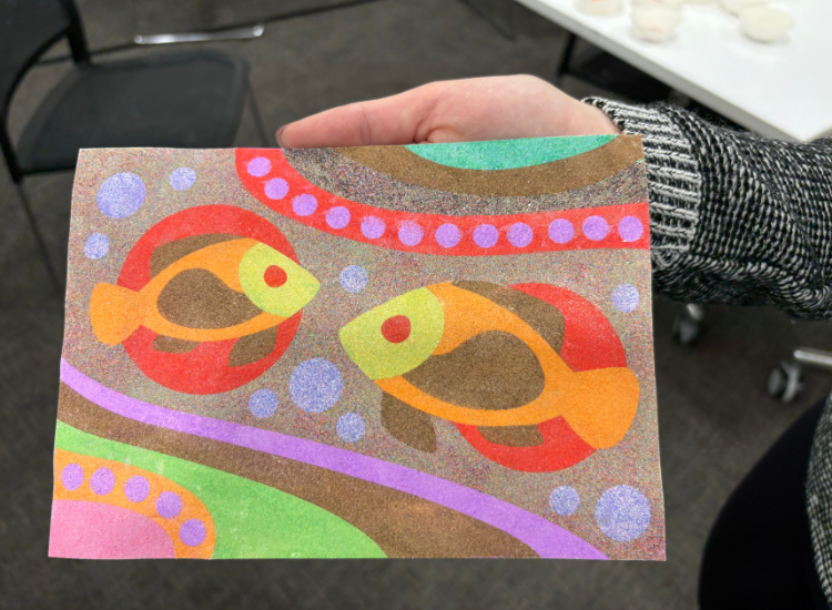 A colourful artwork made of sand depicting two fish