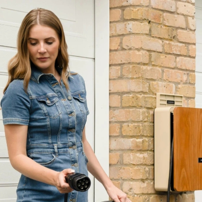 A woman holding an electric vehicle charger.