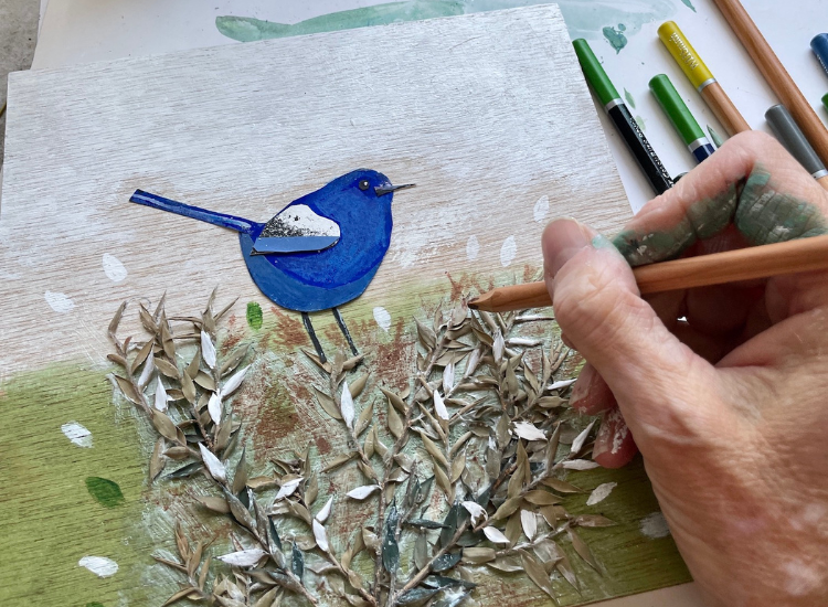 a hand holding a pencil drawing a tree with a blue bird