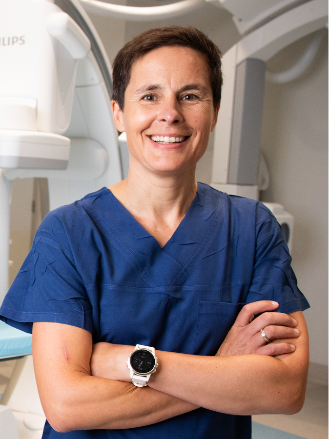 A smiling woman stands with arms folded