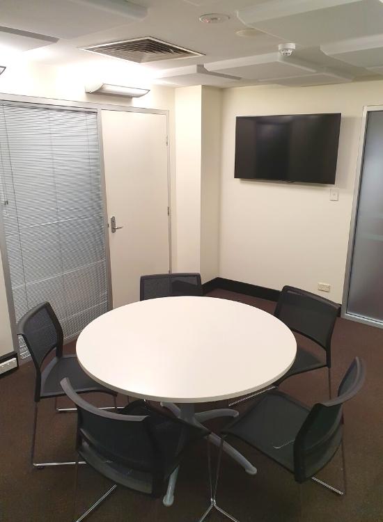 Medium round table with 5 chairs in room with wall mounted television