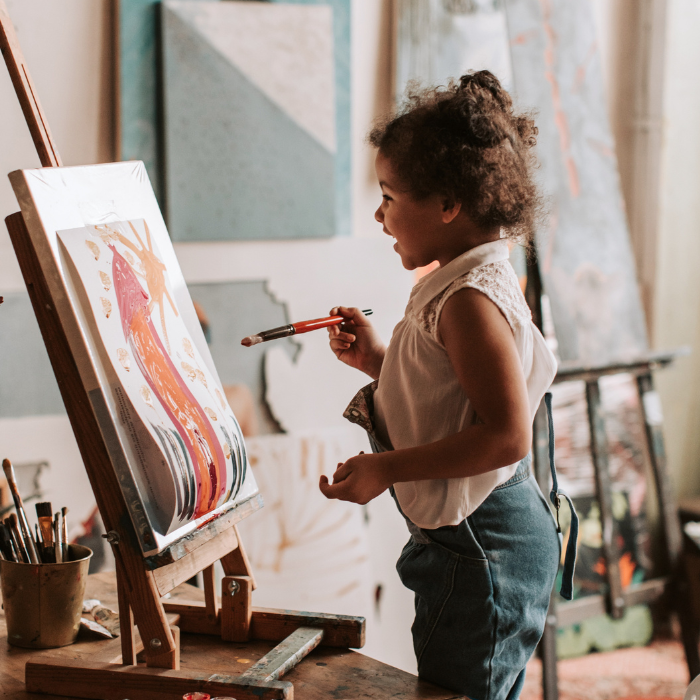 Image of a small child painting on a canvas.