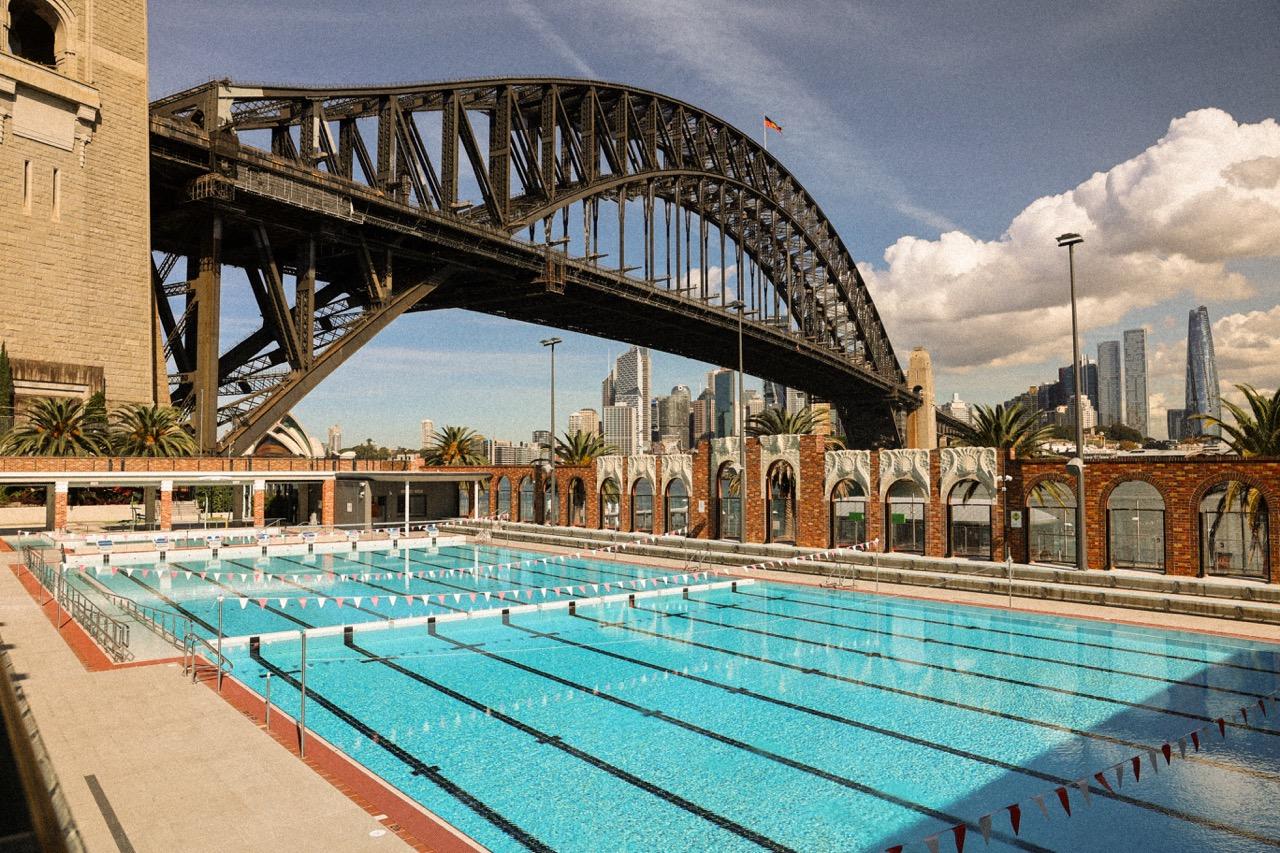 A swimming pool with marked lanes seen in front of a large bridge