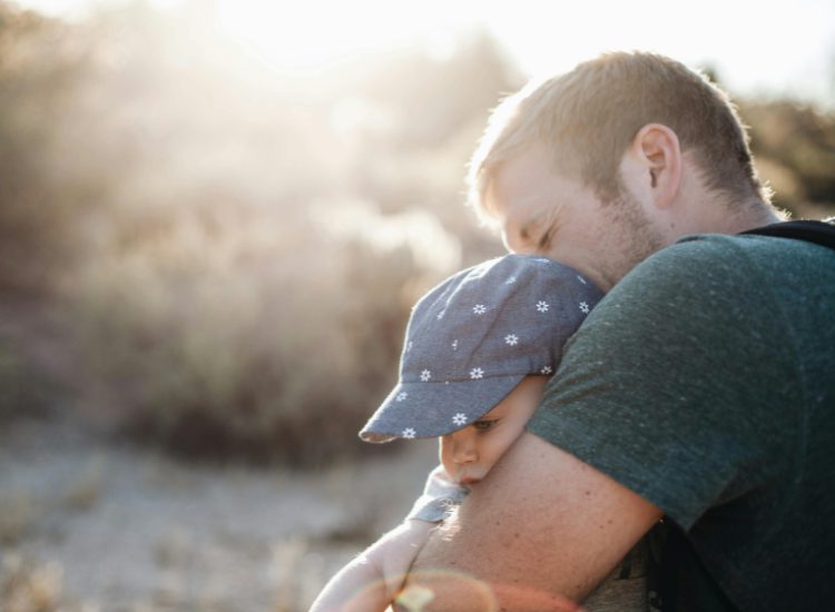 A man embracing a small child wearing a hat