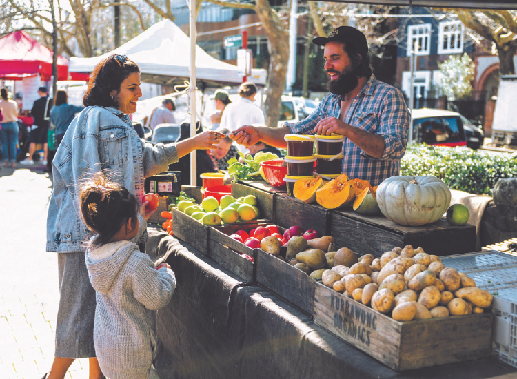 Woman and child paying a man at a produce stand at a market