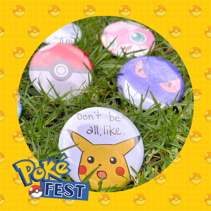 Photo of a few badges with Pokemon memes and drawings laid out on the grass.
