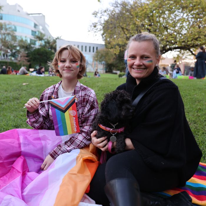 A woman and a chid sit in Ted Mack Civic Park at Pride Picnic