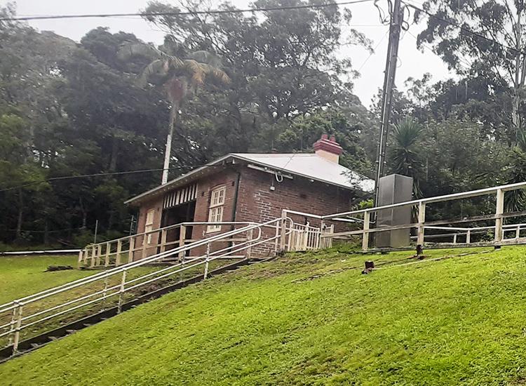 small red brick cottage on green grass.