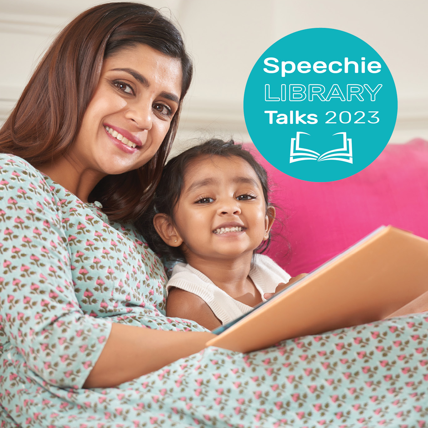 A mother reading to her daughter and smiling at the camera