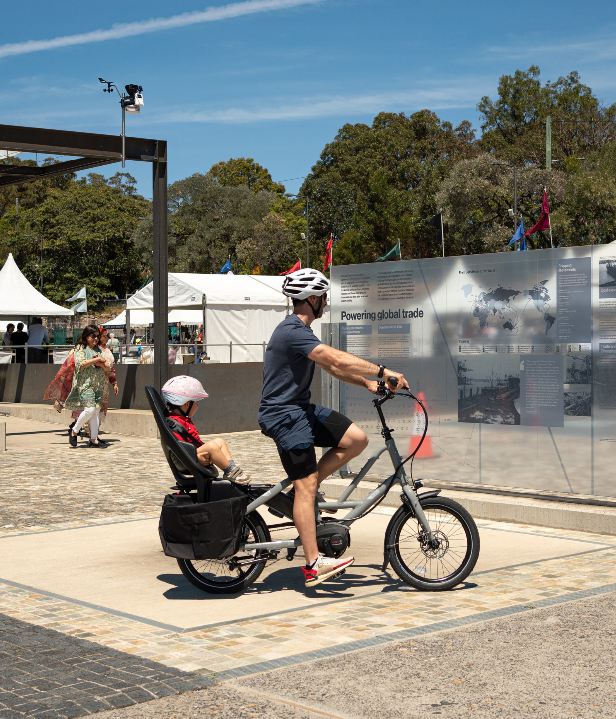 a man riding a bike along a path. The bike has a kids seat on the back with a child in it.