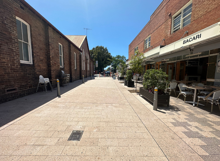 a paved road in between two building with plant boxes on either side.