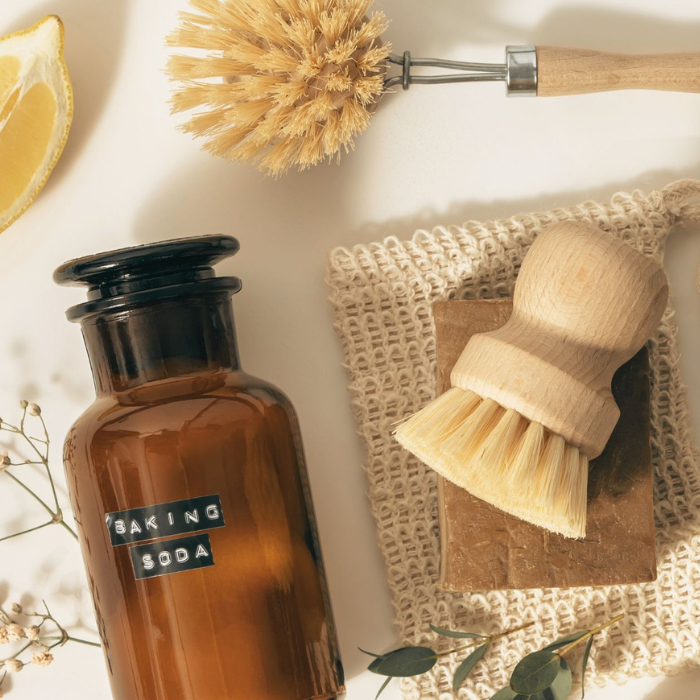 green cleaning products including glass baking soda bottle, brush and soap