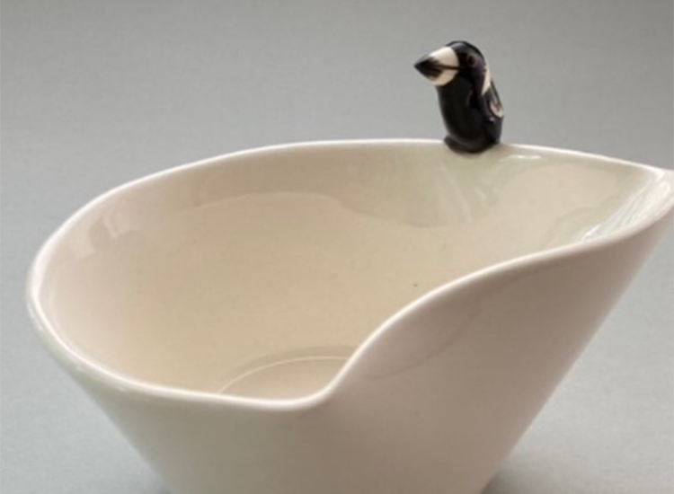 White ceramic bowl with small bird on edge