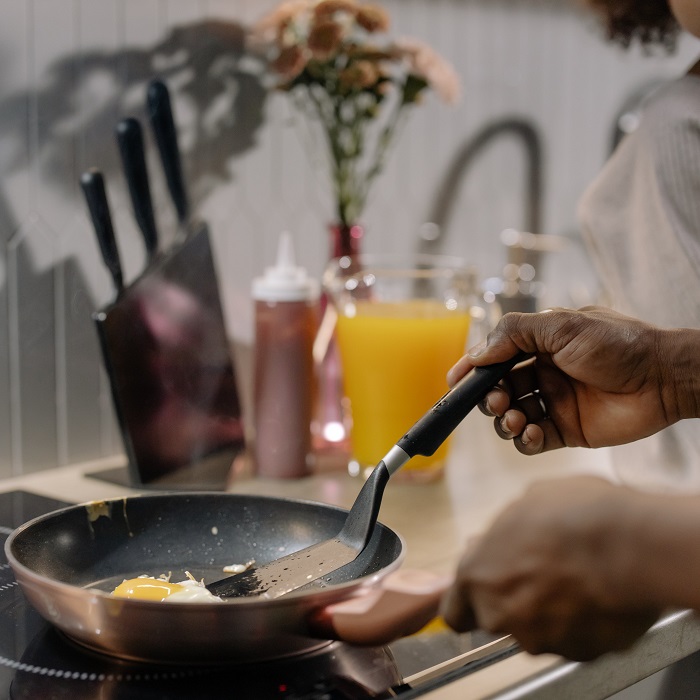 A person cooking an egg in a frypan on an induction cooktop