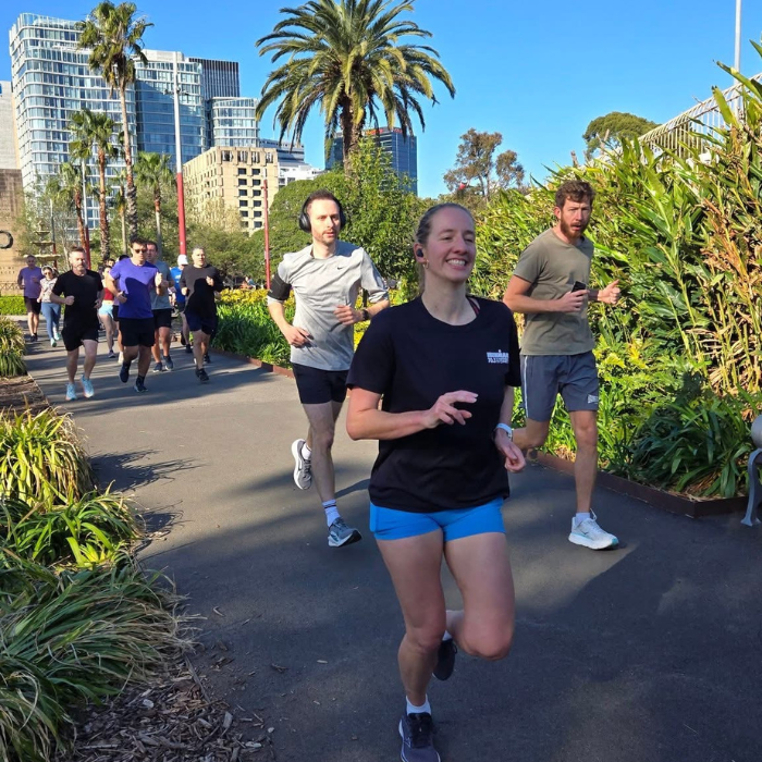 People jogging along a paved path on a sunny day