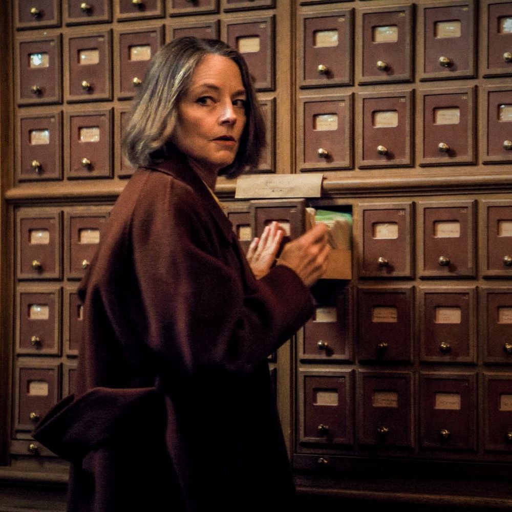 Woman in brown coat and bob-length hair checking mailboxes