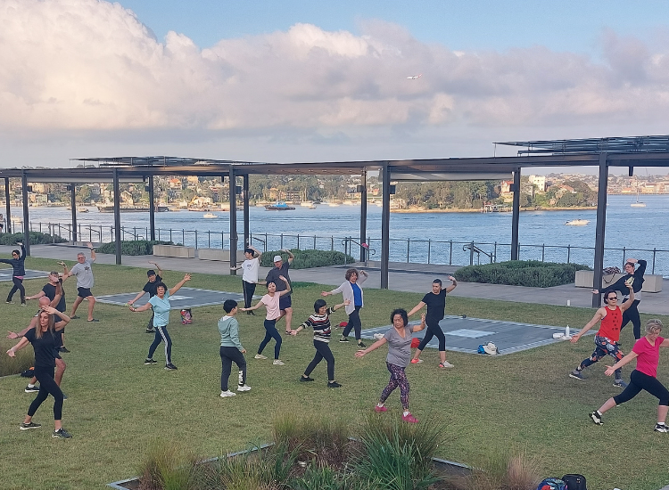 A group of people exercising on the grass of the Coal Loader platform